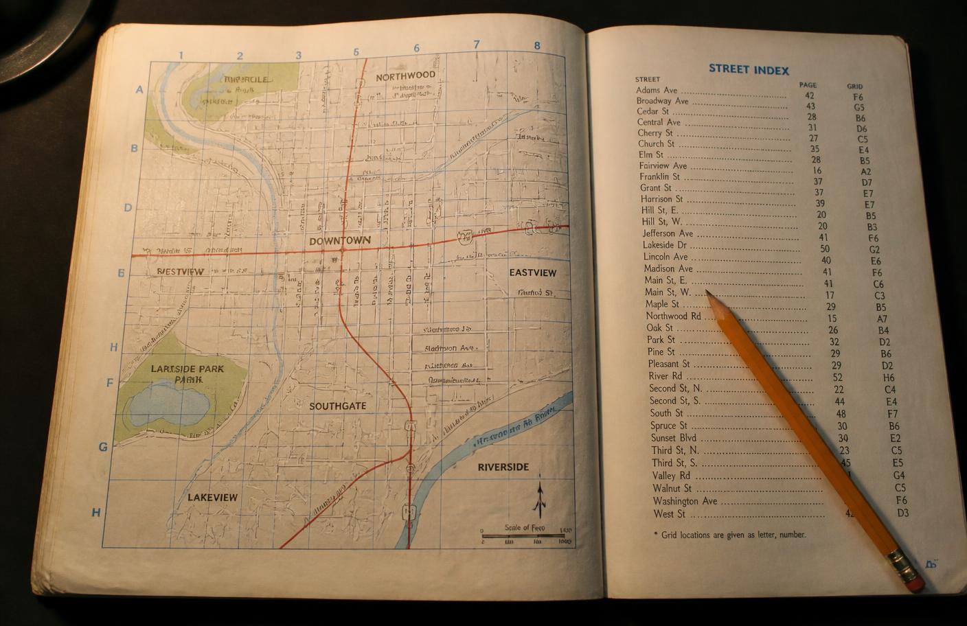 An open map book showing a gridded street map page beside an alphabetical street index listing page numbers and grid references